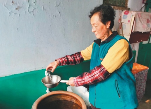 自来水入户,安全又方便。图为辽阳县柳壕镇罗套村村民周秀云“炫耀”着刚刚用上的自来水。(摄影:许刚)