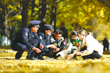 民警和辽东学院学生共同拾捡树叶