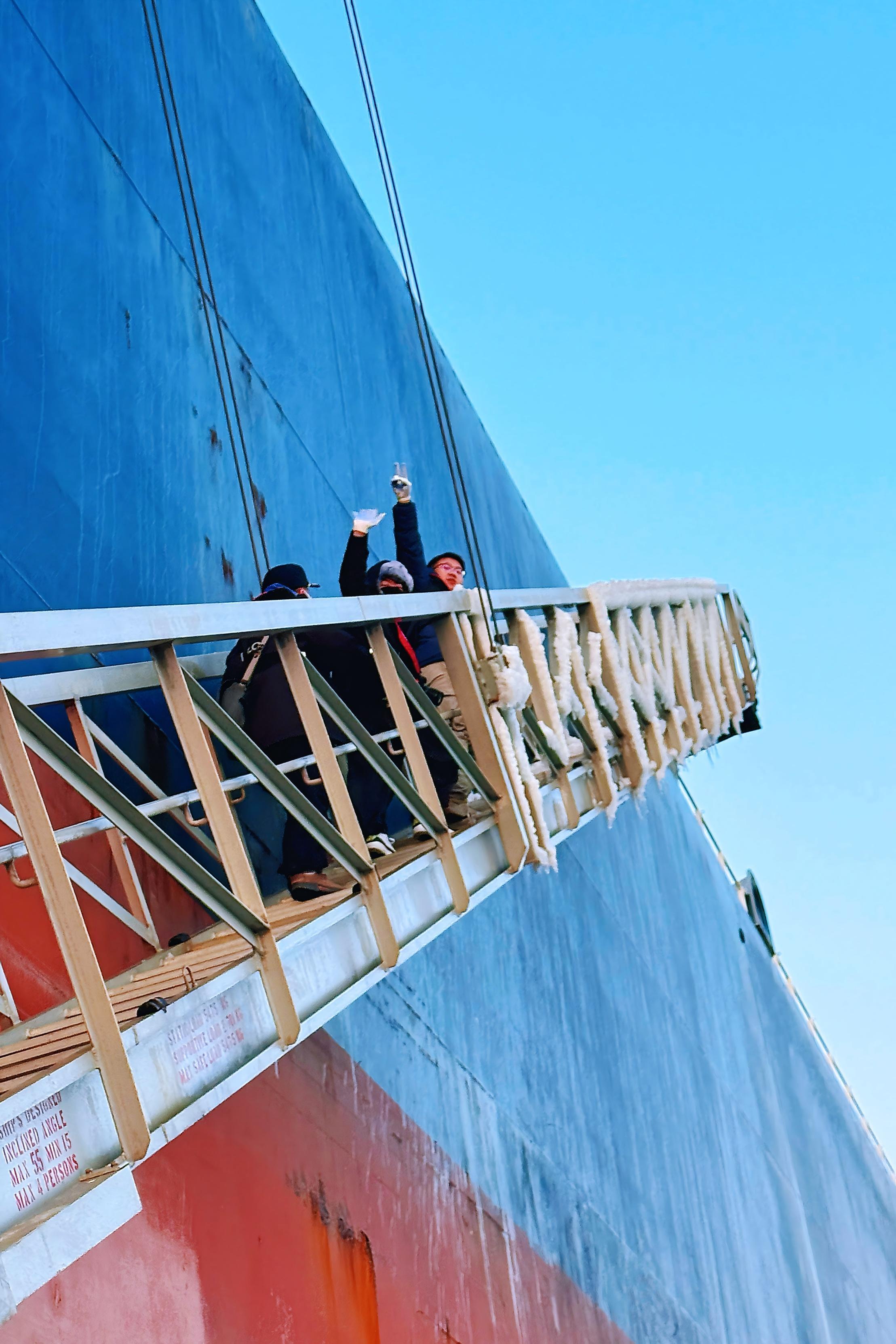 记者白复海（右二）与黄瀚博（右一）随引航员攀爬悬梯登船。 （摄影：王巍）