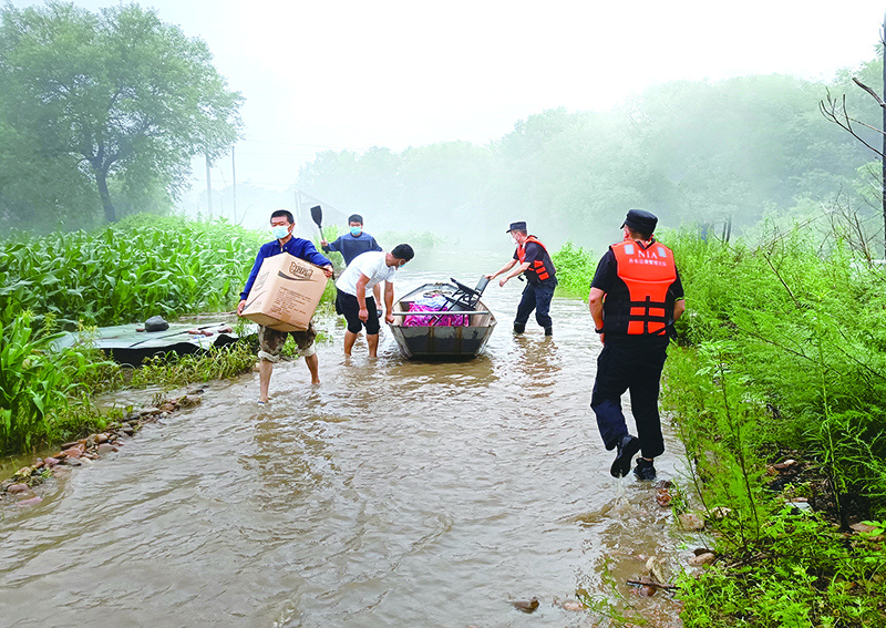 民警、消防人员等合力将被困村民家中财物转移至安全区域。(吴琼 摄)