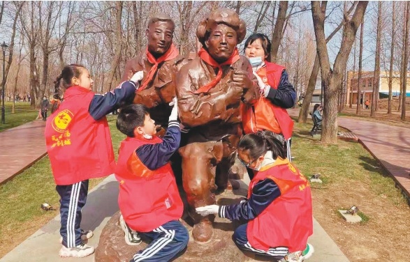 小志愿者在志愿军公园清洁雕塑。