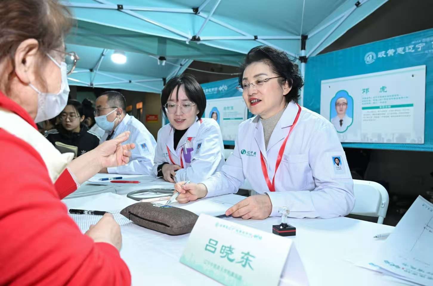 辽宁中医药大学教授吕晓东（右一）为游客义诊。（摄影：查金辉）