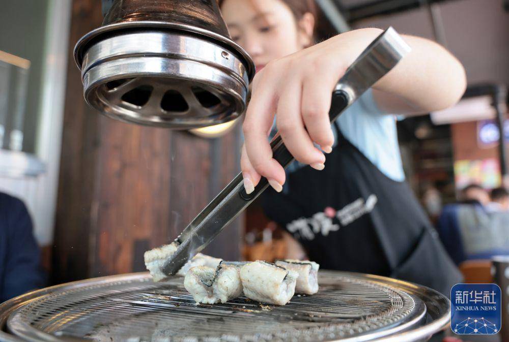在沈阳西塔一家烤肉店，服务员在帮助客人烤鳗鱼（7月28日摄）。新华社记者 李钢 摄