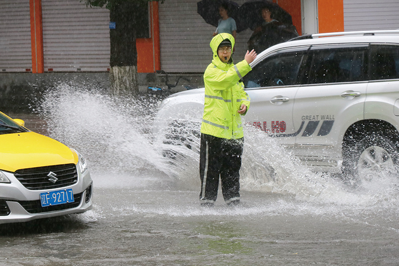 8月16日7点，交警支队振兴一大队辅警曹家瑞上岗指挥交通。当天9点30分，七经街和三纬路路口积水没过脚踝，曹家瑞在暴雨中指挥来往车辆安全有序地通过涉水区域。肖航 摄
