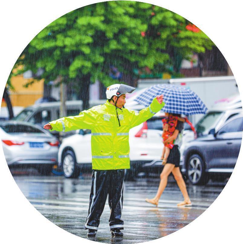 汛期,丹东交警坚守一线,冒雨在城市主干道指挥交通。(摄影:周广庆)