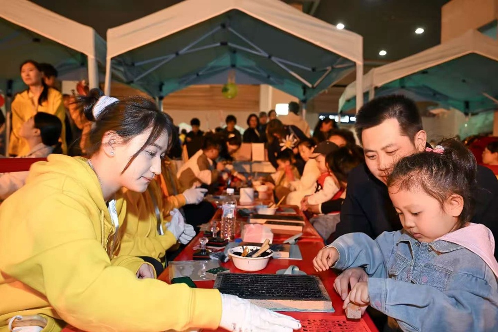 夜市上，游客可以品养生茶、做中药香包、学习中医知识。图为儿童在体验古医书拓印。（摄影：查金辉）