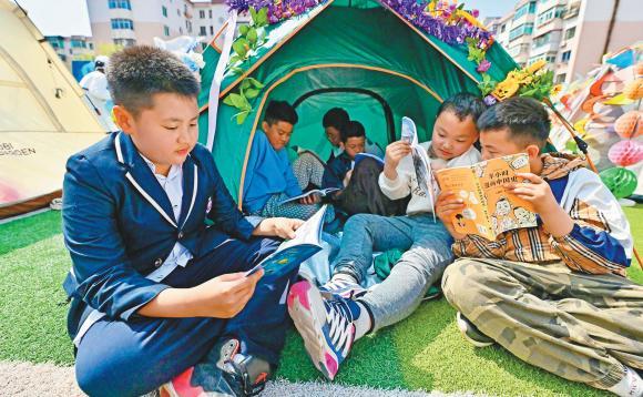 图为本溪市明山区实验小学阅读综合实践活动现场，操场变成读书露营地，同学们在亲手搭建的“书窝”中感受阅读的乐趣。（摄影：林林）