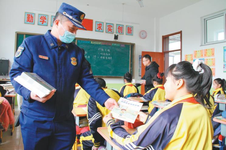 宽甸满族自治县消防救援大队宣传人员为小学生发放消防安全教育手册。(摄影:赵福来)