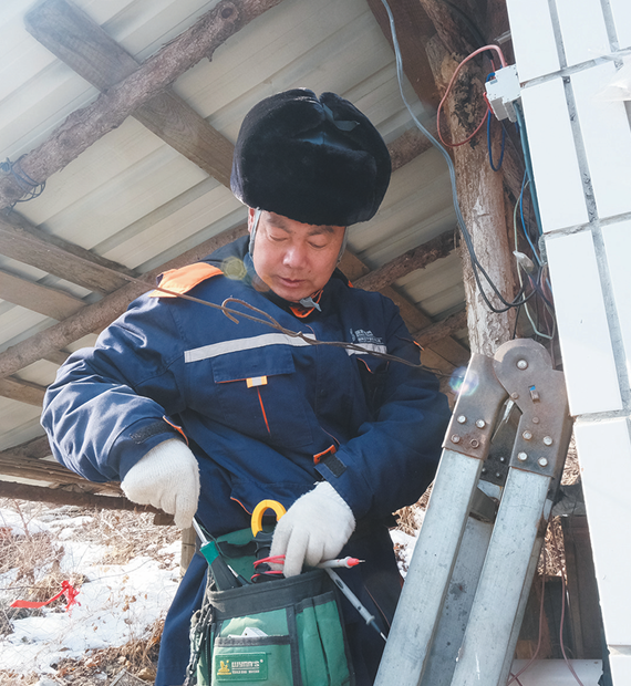 王同宝登上梯子，为老乡家维修电路。（李曼 摄）